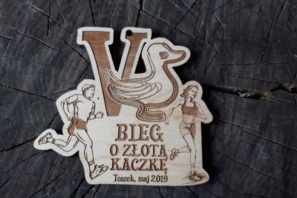 Ekologiczny medal drewniany na zawody biegowe, pamiątka z Biegu o Kaczkę, grawerowany medal z drewna z logo biegu.