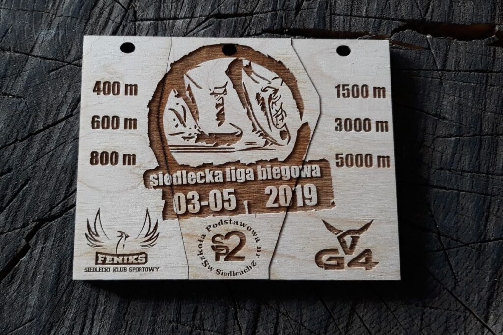 Zestaw trzech drewnianych medali tworzących spójną grafikę, umieszczonych w dopasowanych wycięciach na drewnianej tablicy z napisem Siedlecka Liga Biegowa.