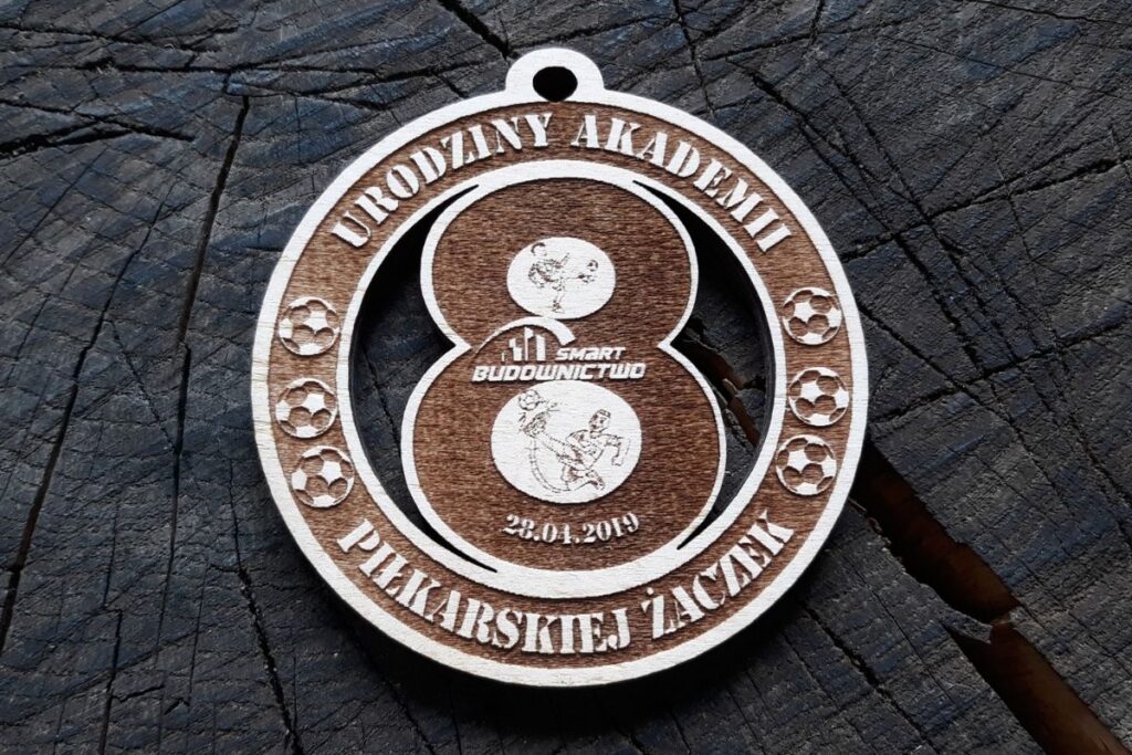 Ażurowy medal z drewna dla dzieci, pamiątka na jubileusz akademii piłkarskiej, ekologiczne trofeum sportowe wycinane laserem.