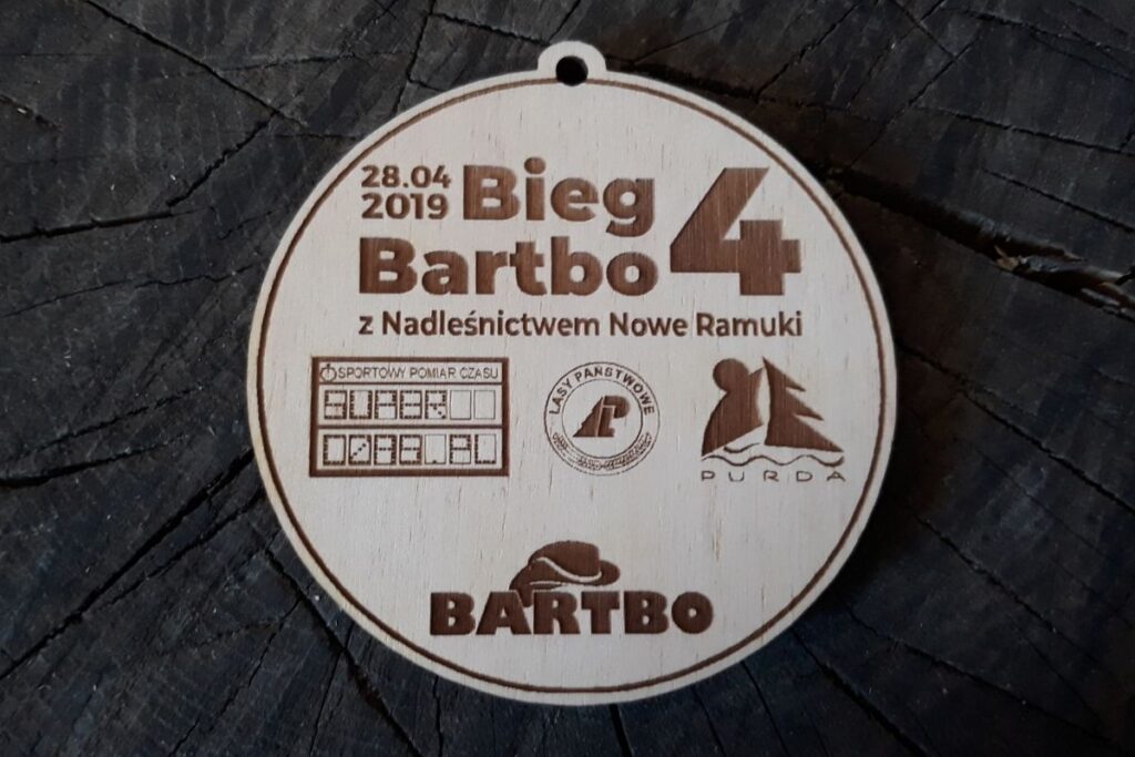 Okrągły drewniany medal z napisem 4 Bieg Bartbo i 4 logotypami.