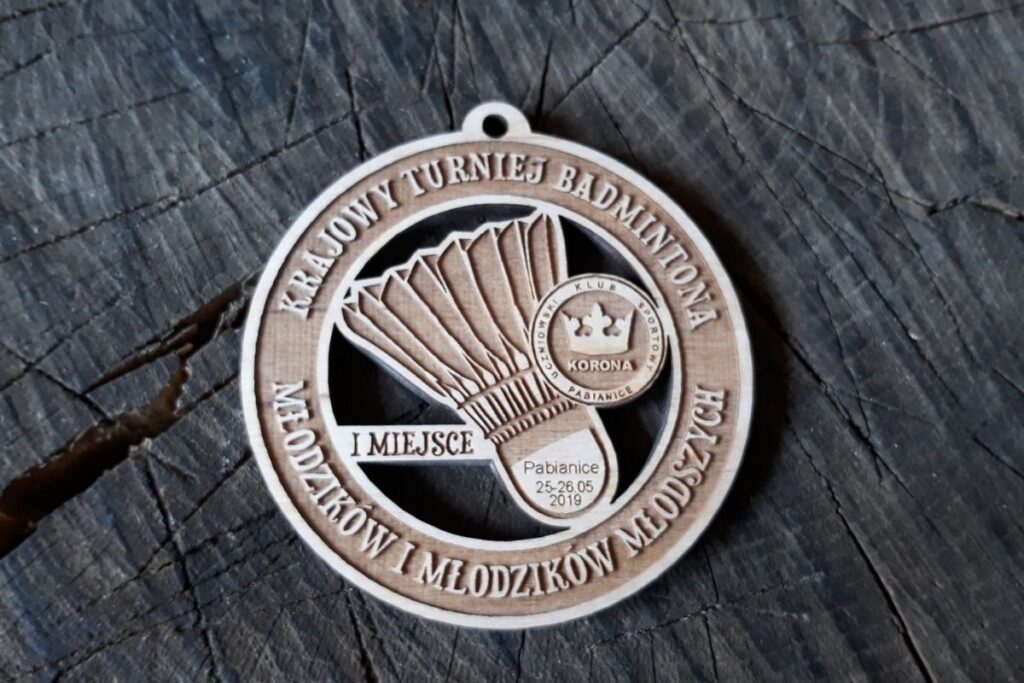 Drewniany medal ażurowy na turniej badmintona z wyciętym laserowo motywem lotki oraz precyzyjnym grawerem napisu Krajowy Turniej Badmintona.