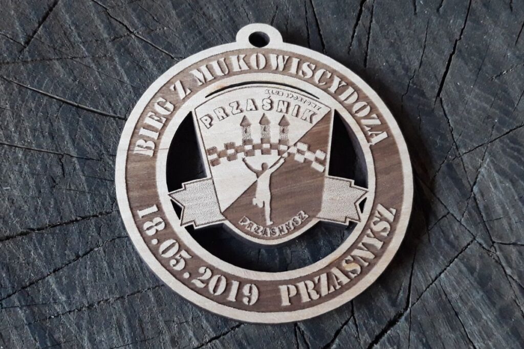 Ażurowy medal charytatywny z drewna, ekologiczne trofeum sportowe, pamiątka z biegu wspierającego chorych na mukowiscydozę, grawer laserowy.”