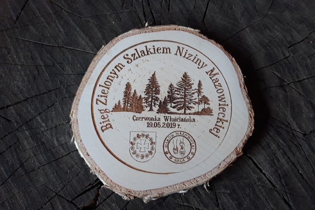 Medal wykonany z naturalnego plastra drewna z korą, grawerem lasu i  napisem Bieg Zielonym Szlakiem Niziny Mazowieckiej.