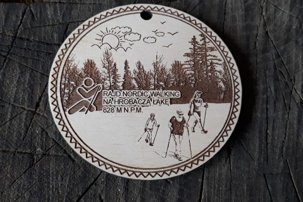 Okrągły drewniany medal sportowy z grawerowaną postacią maszerującą z kijkami oraz napisem Rajd Nordic Walking.