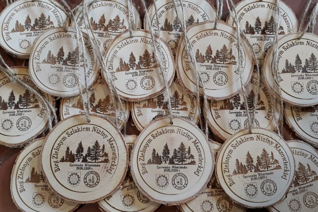 Medal wykonany z naturalnego plastra drewna z korą, grawerem lasu i  napisem Bieg Zielonym Szlakiem Niziny Mazowieckiej.