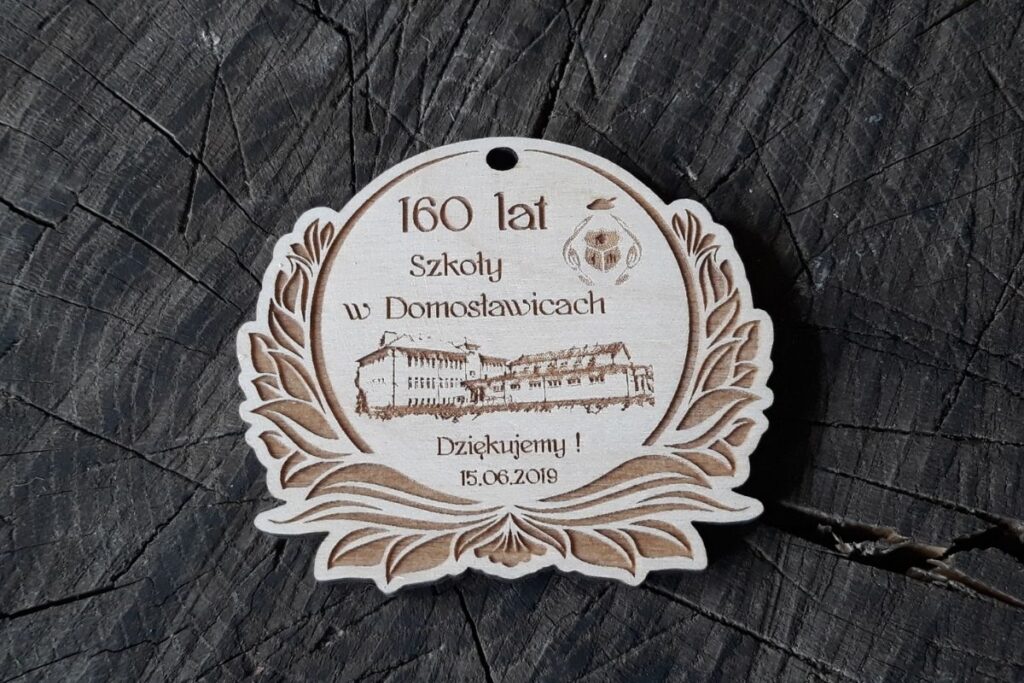 Drewniany medal jubileuszowy dla szkoły, pamiątka na 160-lecie szkoły w Domosławicach, grawerowany medal z budynkiem szkoły, medal okolicznościowy z drewna.