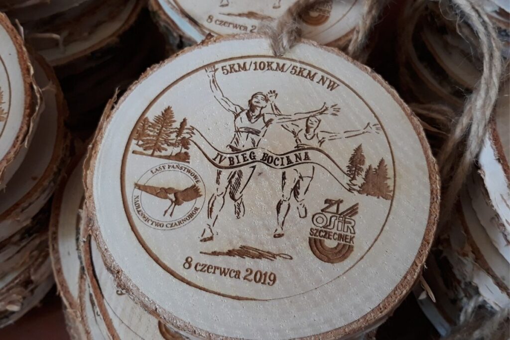 Medal z plastra drewna z korą, ekologiczne trofeum Bieg Bociana, pamiątka z biegu na plastrze brzozy, grawerowany medal naturalistyczny.