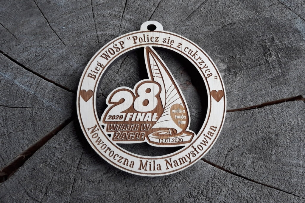 Okrągły drewniany medal na Finał WOŚP z grawerem charakterystycznego serca, napisem Bieg i Marsz oraz datą finału.