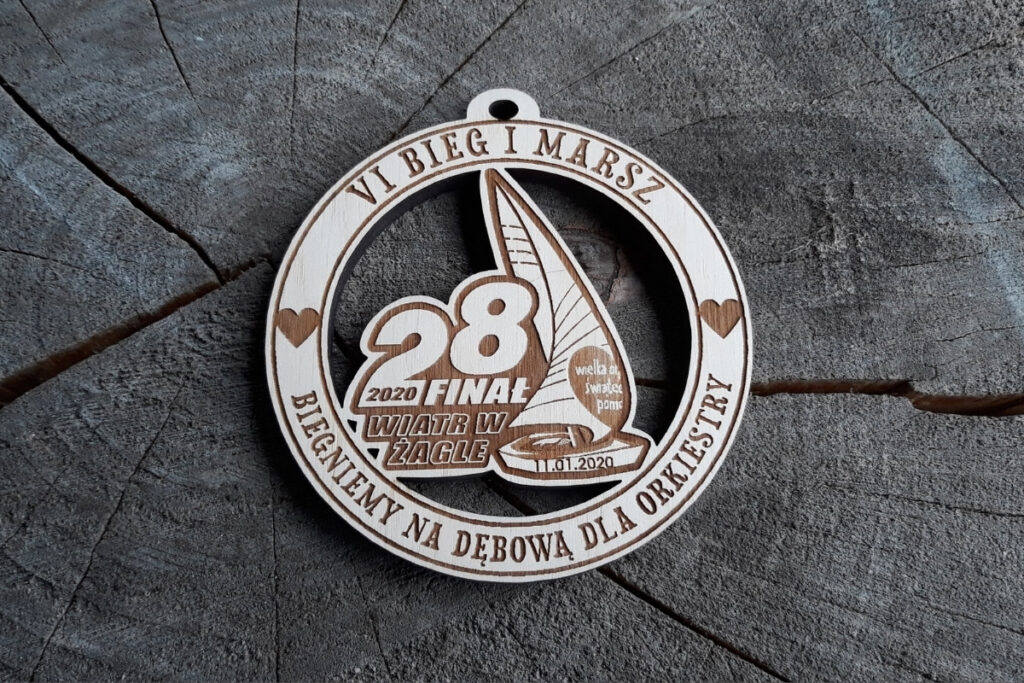 Okrągły drewniany medal na Finał WOŚP z grawerem charakterystycznego serca, napisem Bieg i Marsz oraz datą finału.