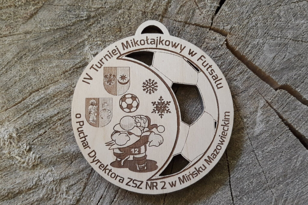 Okrągły drewniany medal na turniej futsalu z grawerem Mikołaja - jako piłkarza - w akcji, napisem IV Turniej Mikołajkowy.