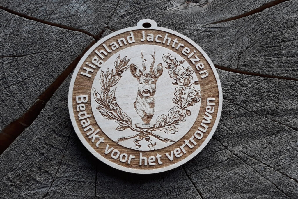 Okrągły drewniany medal z precyzyjnym grawerem głowy koziołka (sarny) w otoczeniu klasycznego wieńca dębowego.