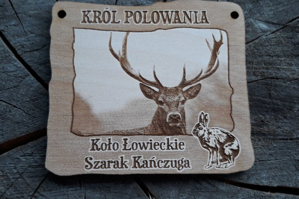 Prostokątny drewniany medal z niezwykle szczegółowym, fotorealistycznym grawerem głowy jelenia byka, napisem Król Polowania i napisami.