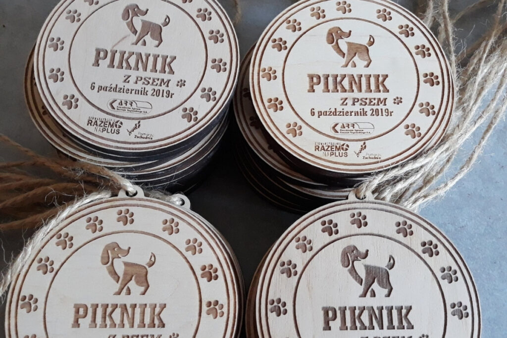 Okrągły drewniany medal z grawerem psich orz napisem Piknik z Psem.