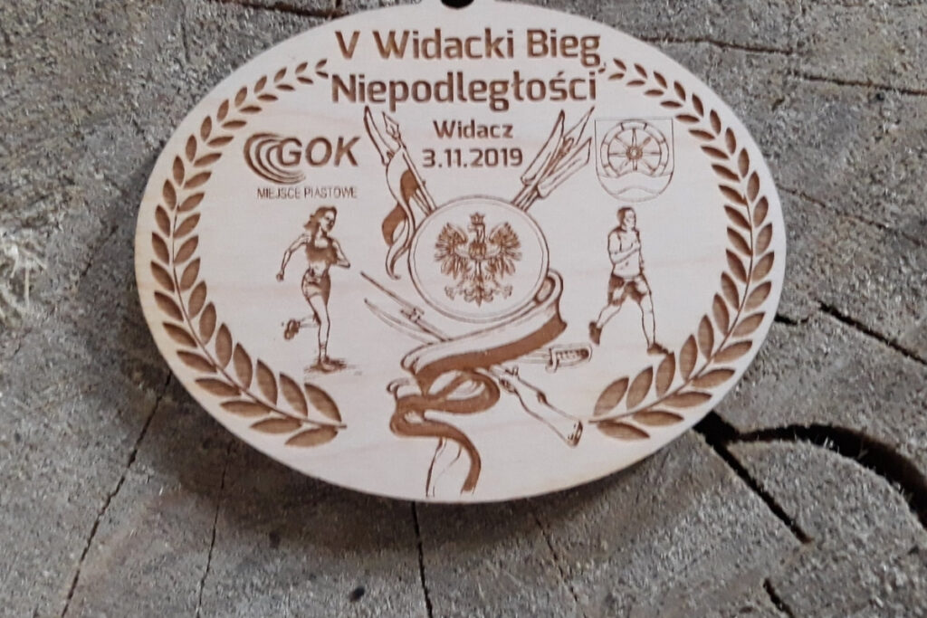 Owalny drewniany medal z grawerem godła Polski – orła w koronie, datą 11 listopada i napisem Bieg Niepodległości.