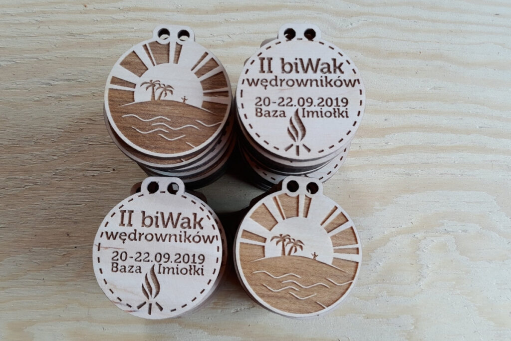 Okrągła drewniana plakietka z grawerem widoków oraz napisami II biWak Wędrownika.