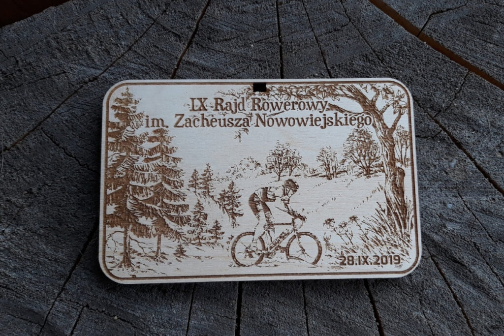 Medal z jasnej płyty brzozowej z precyzyjnym grawerem elementów kojarzących się z rowerami, napisem Rajd Rowerowy i dekoracjami.