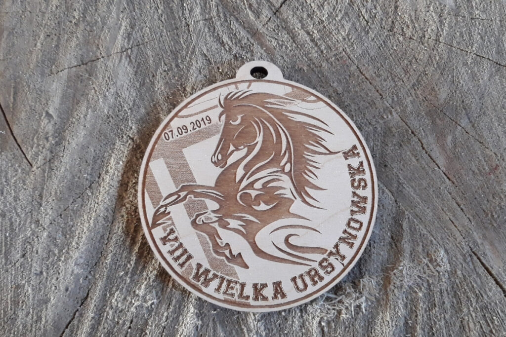 Okrągły drewniany medal z grawerem napisu VIII Wielka Ursynowska, sylwetką biegnącego konia i napisem Warszawa 2019.