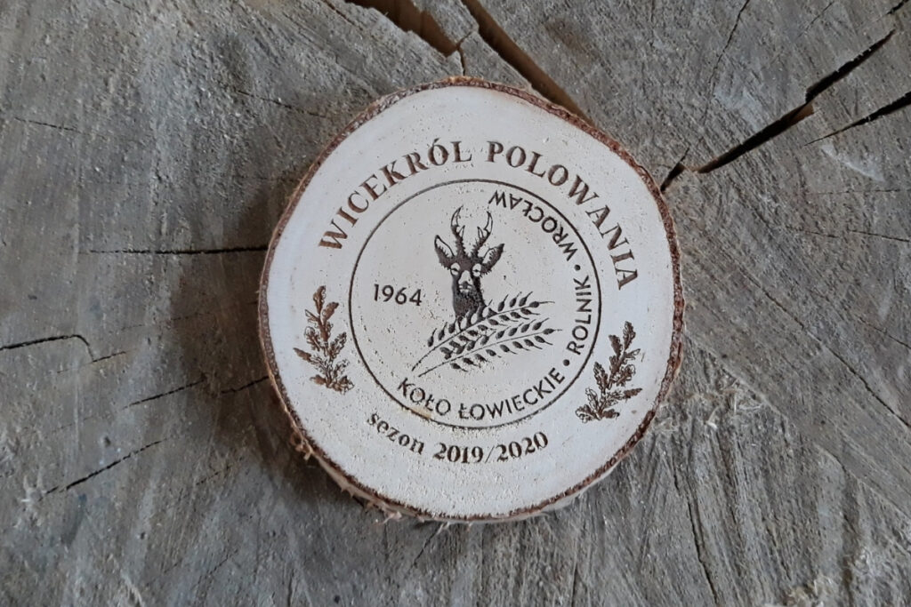 Medal z naturalnego plastra brzozy z korą, z grawerem głowy jelenia, napisem Wicekról Polowania i ozdobnymi gałązkami.