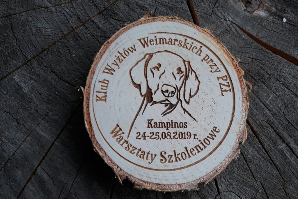 Medal z naturalnego plastra brzozy z korą, z grawerem logotypu Klubu Wyżłów Weimarskich i napisem Warsztaty Szkoleniowe.