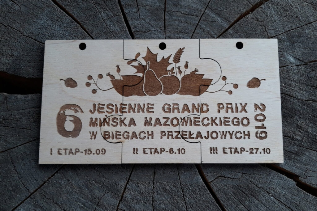 rzy drewniane medale o dopasowanych kształtach, które po złożeniu tworzą prostokątną tabliczkę z motywem jesiennych liści i napisem Jesienne Grand Prix.