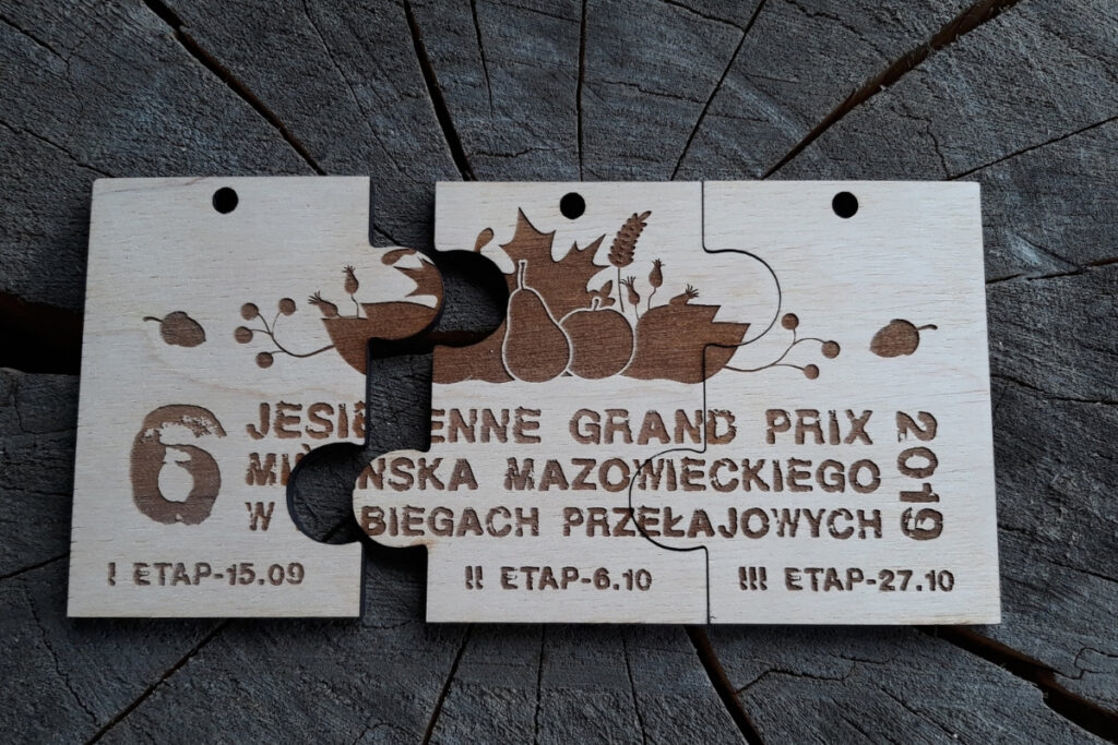 rzy drewniane medale o dopasowanych kształtach, które po złożeniu tworzą prostokątną tabliczkę z motywem jesiennych liści i napisem Jesienne Grand Prix.