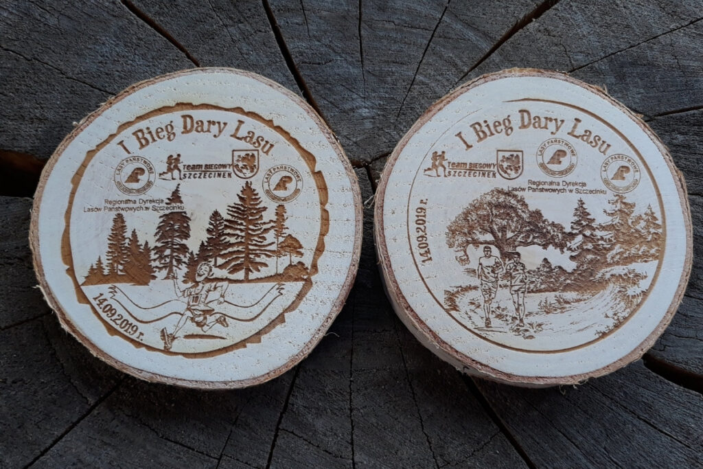 Medal z naturalnego plastra brzozy z korą, z grawerem napisu Dary Lasu, logotypów, w konwencji leśnej.