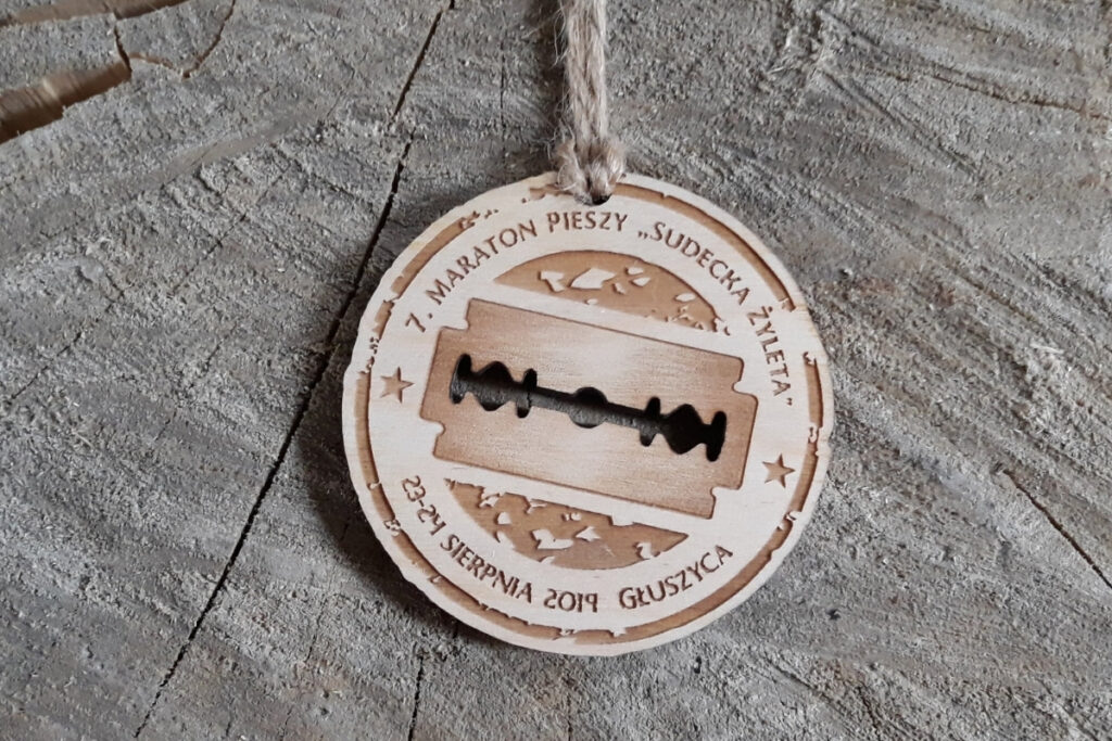 Okrągły drewniany medal z logotypem Sudecka Żyleta i napisem Maraton Pieszy.