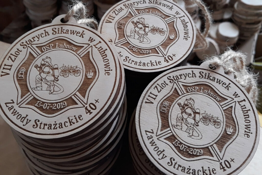 Okrągły drewniany medal z grawerem zabytkowej sikawki konnej, herbem OSP oraz napisem VII Zlot Starych Sikawek Strażackich w Lubnowie.”