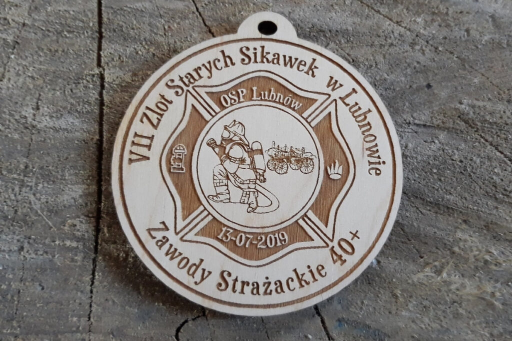 Okrągły drewniany medal z grawerem zabytkowej sikawki konnej, herbem OSP oraz napisem VII Zlot Starych Sikawek Strażackich w Lubnowie.”