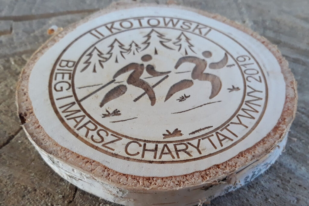 Medal wykonany z naturalnego plastra brzozy z korą, z grawerem logotypu Kotowskiego Biegu i Marszu.