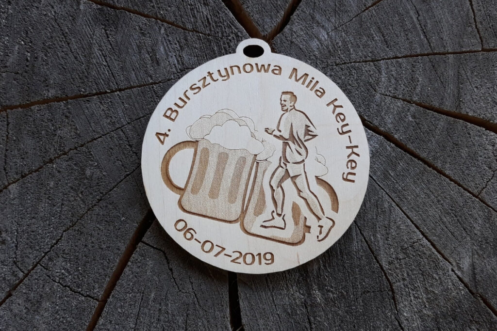 Okrągły drewniany medal z grawerem biegnącego zawodnika, dwóch kufli z pianką i napisem 4. Bursztynowa Mila.