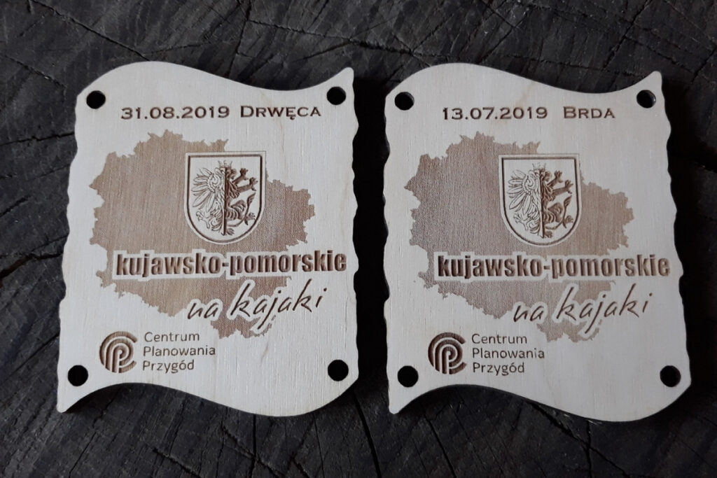 Zestaw dwóch drewnianych medali z grawerem mapy, które po złączeniu tworzą dopasowaną tabliczkę.