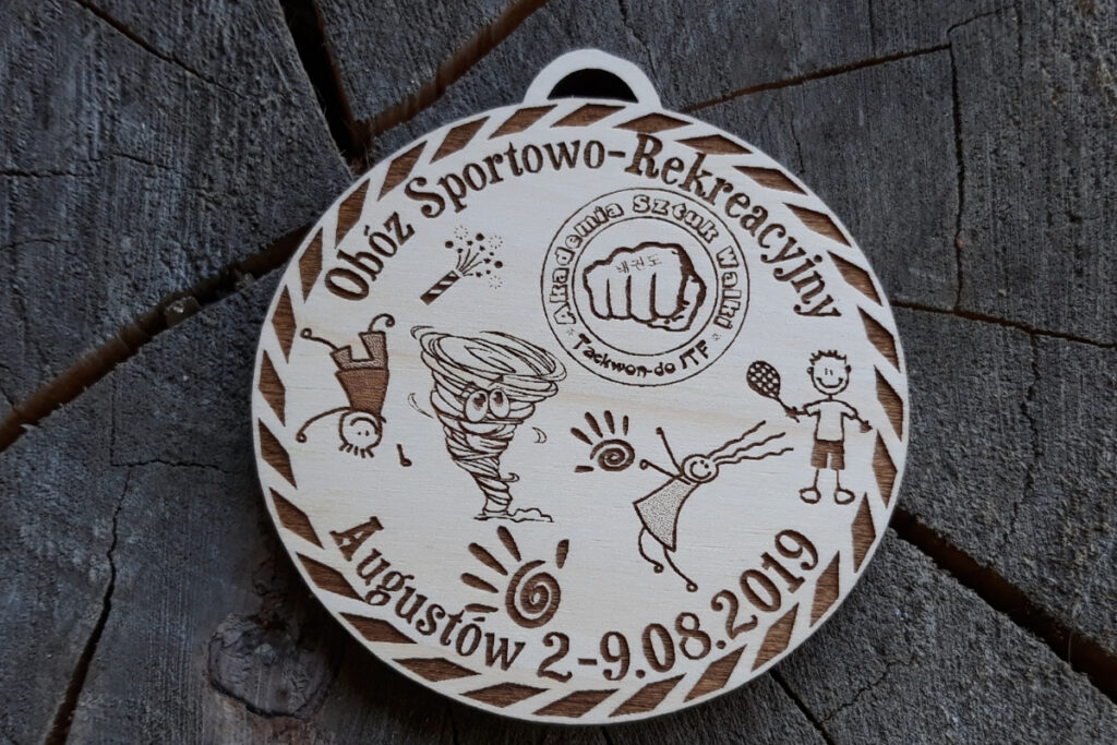 Drewniany medal dla dzieci z grawerem dzieci grających w piłkę, siatkę, badmintona, koszykówkę, logotypem i napisami.