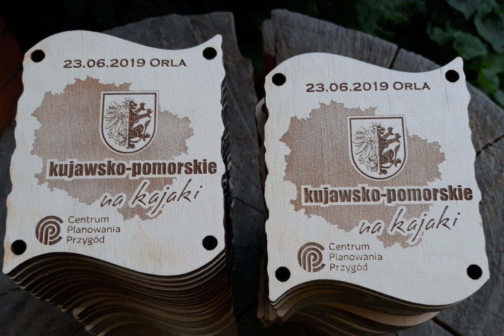 Zestaw dwóch drewnianych medali z grawerem mapy, które po złączeniu tworzą dopasowaną tabliczkę.