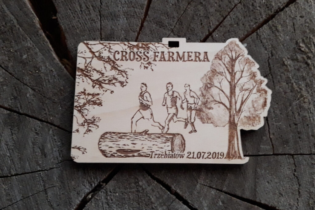 Prostokątny drewniany medal z grawerem rozłożystego drzewa, traktora oraz napisem Cross Farmera.