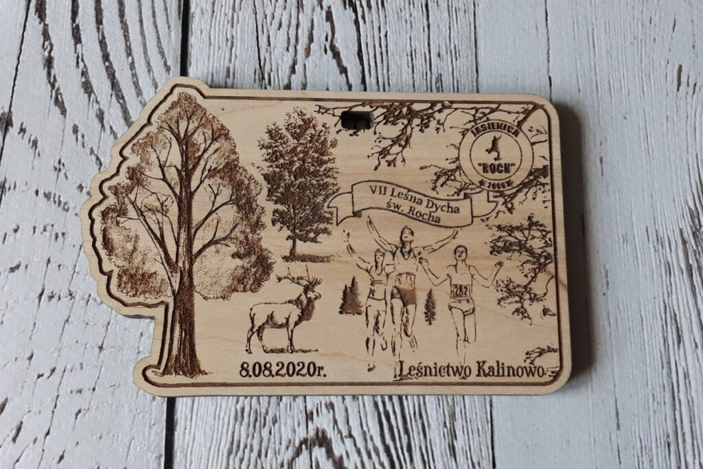 Drewniany medal z grawerem lasu liściastego, stylizowaną nazwą VII Leśna Dycha św. Rocha oraz sylwetkami biegaczy.