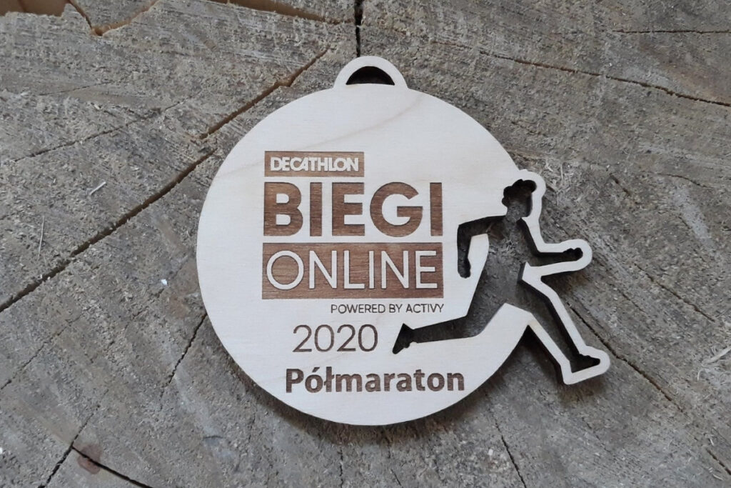 Okrągły drewniany medal ażurowy z precyzyjnie wyciętą sylwetką biegacza w ruchu, personalizowany grawer na biegi wirtualne on-line, wykonany z jasnej brzozy bez przypaleń.