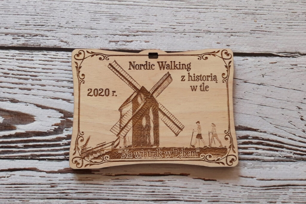 drewniany medal na Marsz Nordic Walking z Historią w Tle, z grawerem historycznego wiatraka typu koźlak, sylwetkami kijkarzy oraz datą wydarzenia, wykonany z czystej brzozy bez osmaleń.
