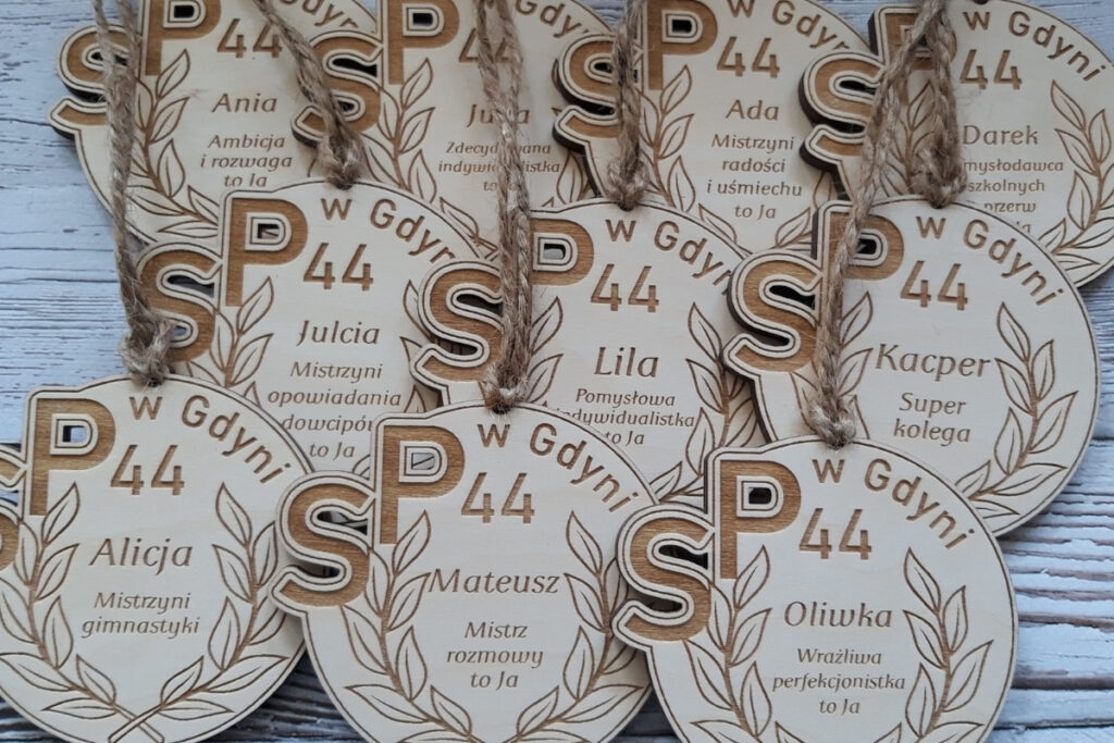 Okrągły drewniany medal na zakończenie roku szkolnego z personalizowanym grawerem imienia dziecka, krótkim tekstem o dziecku, wykonany z czystej brzozy bez osmaleń.