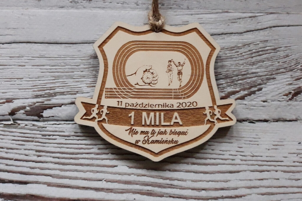 Drewniany medal na Bieg 1-Milowy, z precyzyjnym grawerem bieżni lekkoatletycznej, dużym napisem „1 MILA”, wykonany z czystej brzozy - płyty bez osmaleń.