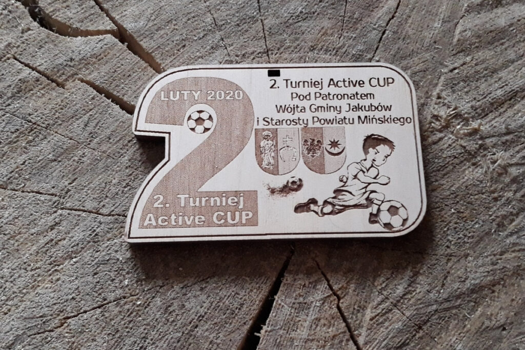 Drewniany medal dla młodych piłkarzy na turniej Active Cup, z grawerem dużej 2, młodym piłkarzem, logotypami, wykonany z jasnej płyty drzewnej bez osmaleń.