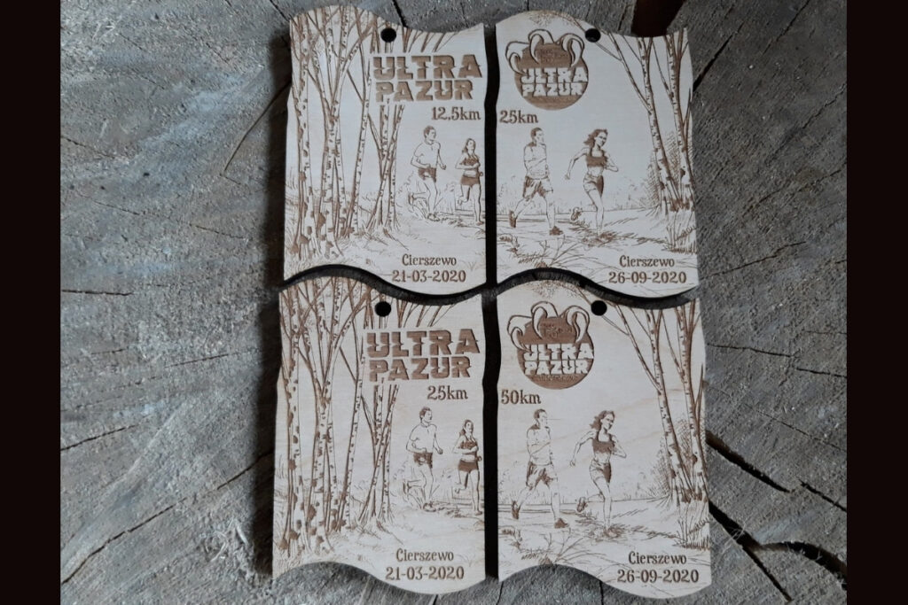 Zestaw dwóch drewnianych medali modułowych na bieg Ultra Pazur, które po złączeniu tworzą prostokątną tabliczkę z motywem drapieżnych pazurów i logotypem biegu, wykonany z czystej brzozy bez śladów dymu.