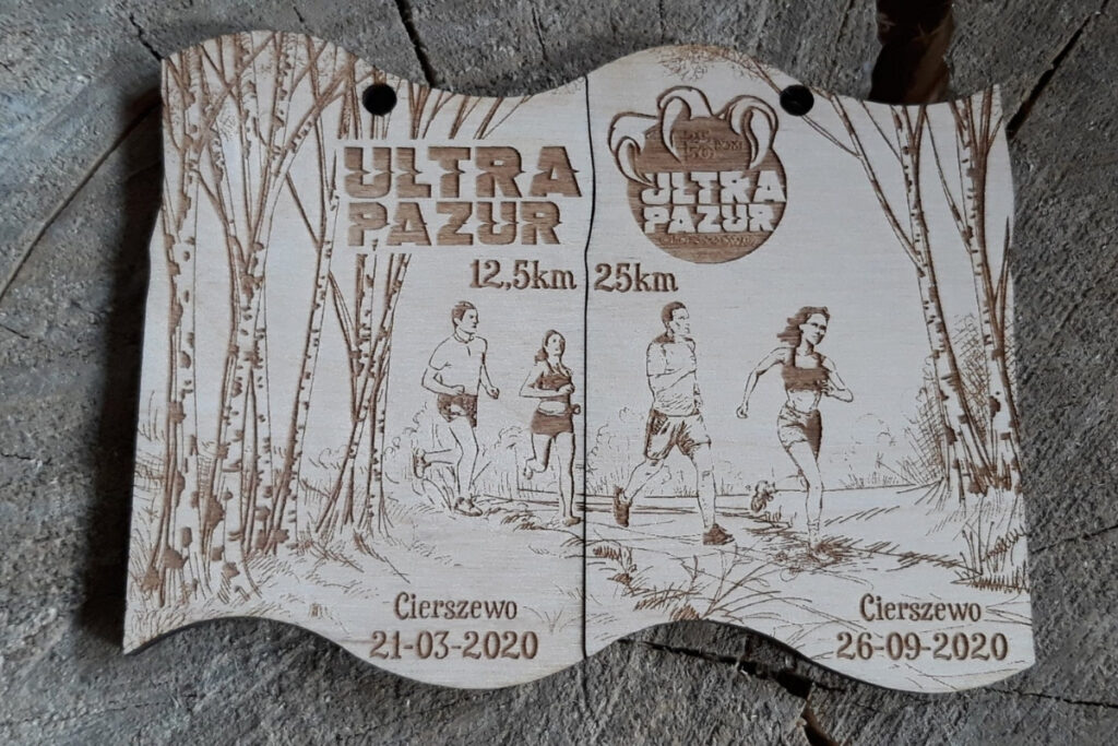 Zestaw dwóch drewnianych medali modułowych na bieg Ultra Pazur, które po złączeniu tworzą prostokątną tabliczkę z motywem drapieżnych pazurów i logotypem biegu, wykonany z czystej brzozy bez śladów dymu.