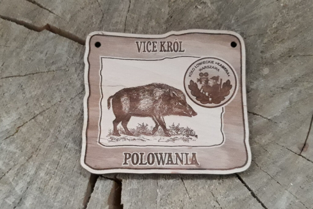 Prostokątny drewniany medal dla Vice Króla Polowania z grawerem biegnącego dzika, oraz logotypem koła łowieckiego, wykonany z jasnej brzozy bez śladów osmaleń.