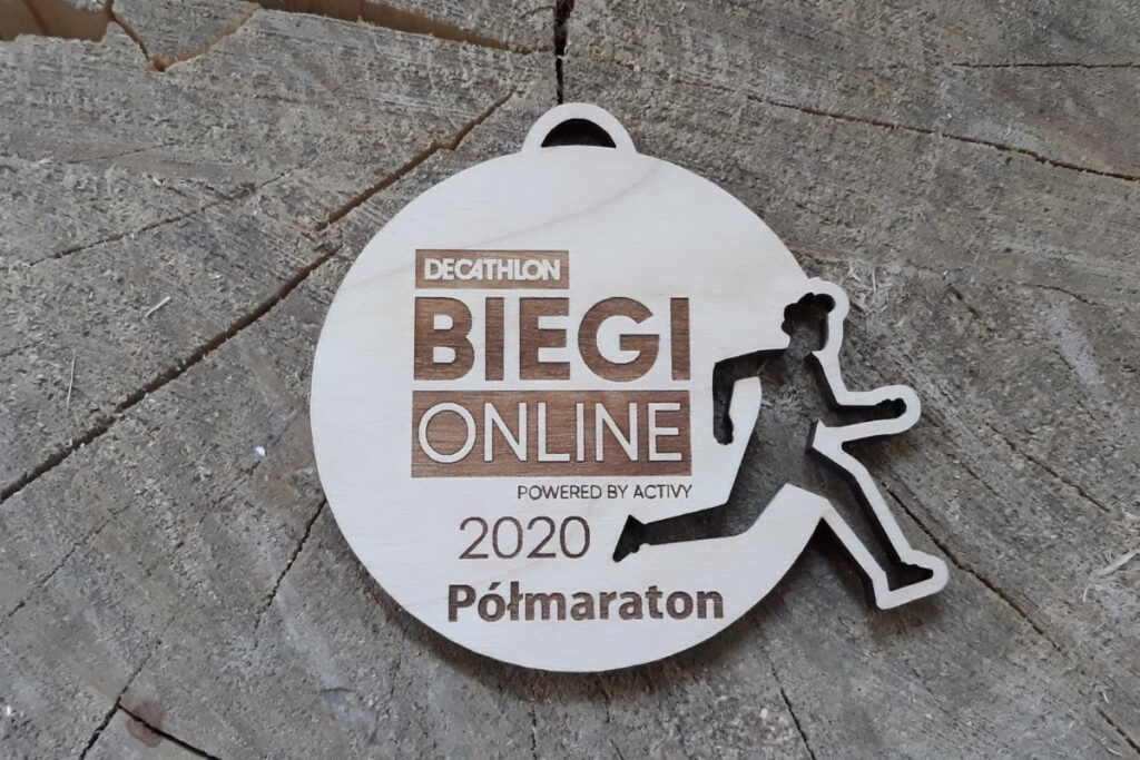 Okrągły drewniany medal ażurowy z precyzyjnie wyciętą sylwetką biegacza w ruchu, personalizowany grawer na biegi wirtualne on-line, wykonany z jasnej brzozy bez przypaleń.