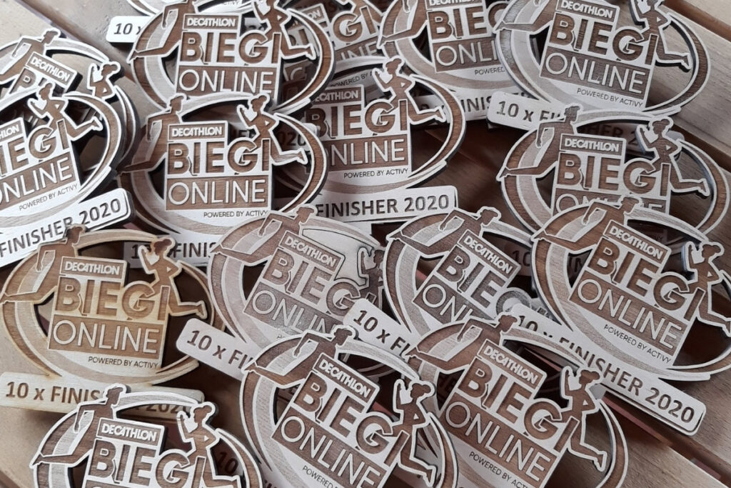 Owalny drewniany medal na Bieg Online z ażurowo wyciętymi sylwetkami biegaczy w ruchu, wykonany z jasnej brzozy bez śladów przypaleń, z grawerem nazwy wydarzenia.