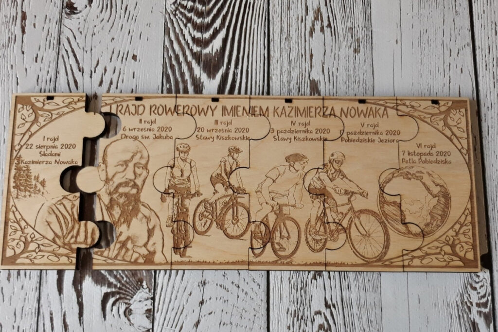 Zestaw sześciu drewnianych medali modułowych na rajd rowerowy, które po złożeniu tworzą prostokątną tabliczkę z grawerem kolarzy na trasie, logotypem wydarzenia i mapą, wykonany z jasnej brzozy bez śladów osmaleń.