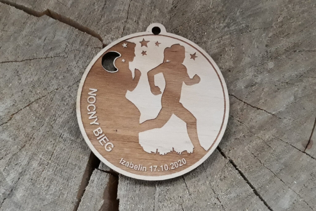 Okrągły drewniany medal na bieg nocny, z precyzyjnym grawerem gwiazd oraz sylwetek biegaczy na tle nocnego nieba, wykonany z czystej płyty brzozowej bez śladów przypaleń czy zabrudzeń.