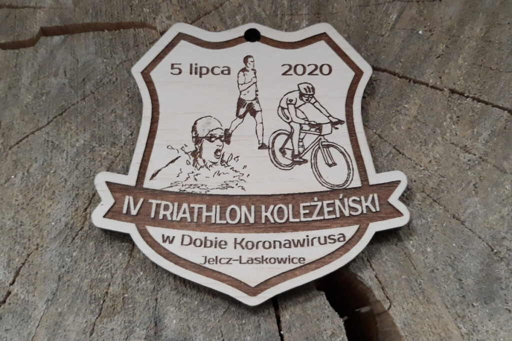 Drewniany medal triathlonowy z grawerowanymi ikonami trzech dyscyplin: pływania, jazdy na rowerze i biegania, wykonany z jasnej płyty brzozy bez śladów dymu.