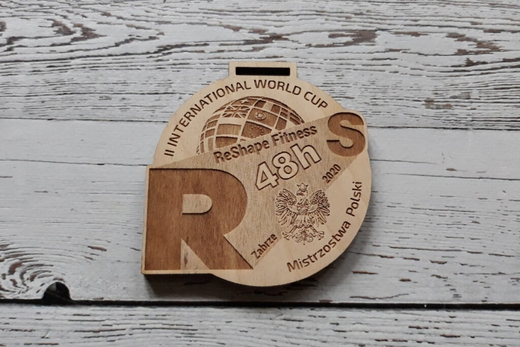 Okrągły drewniany medal na Mistrzostwa Polski z grawerem godła państwowego, dużymi literami R i S .